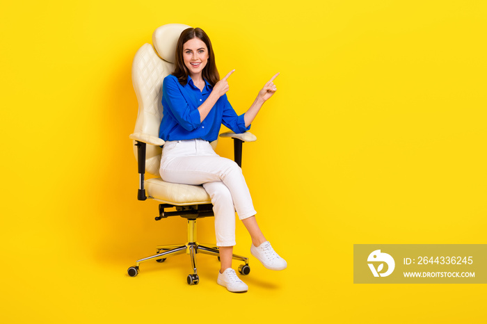 Full length photo of excited business lady wear formal office outfit sitting armchair finger indicate vacancy isolated on yellow color background