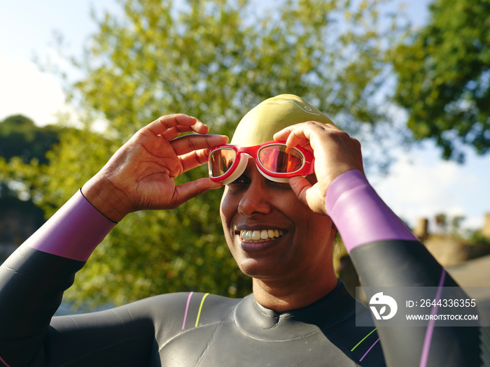 Smiling woman putting on swimming goggles