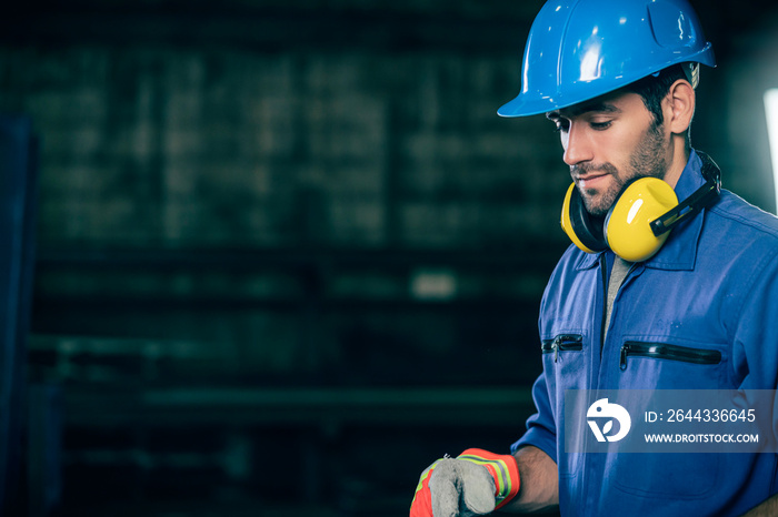 caucasian engineer worker wearing safty blue helmet and uniform with background of factory workshop