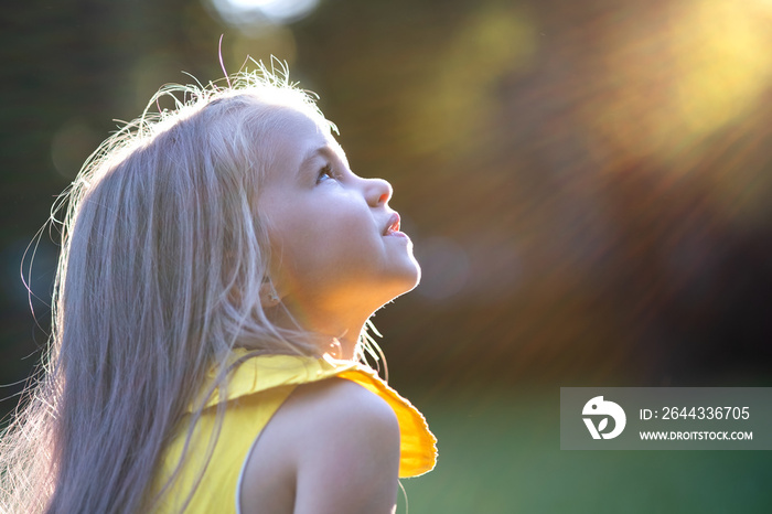 Portrait of happy pretty child girl smiling outdoors enjoying warm sunny summer day.