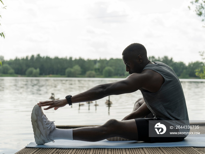 Man stretching on jetty by lake