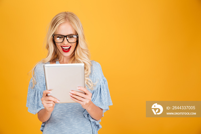 Happy young blonde woman using tablet computer.