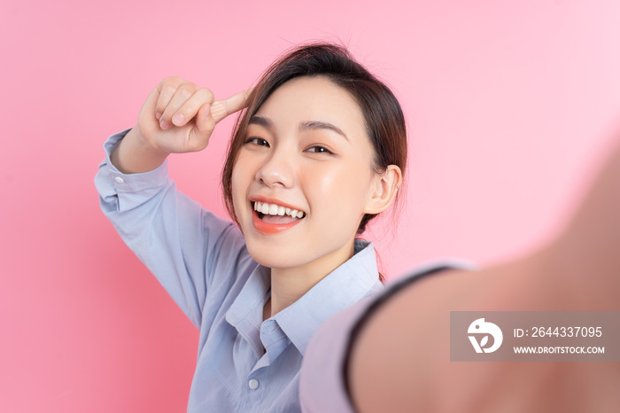 Portrait of young Asian girl posing on pink background