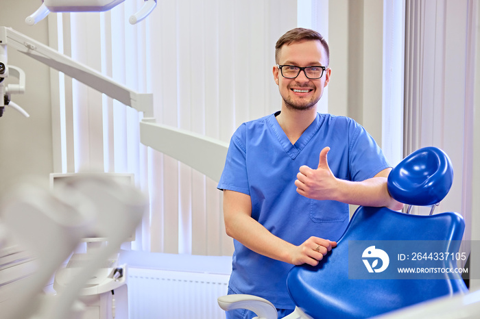 Male dentist in a room with medical equipment on background.