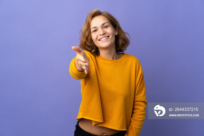 Young Georgian woman isolated on purple background shaking hands for closing a good deal