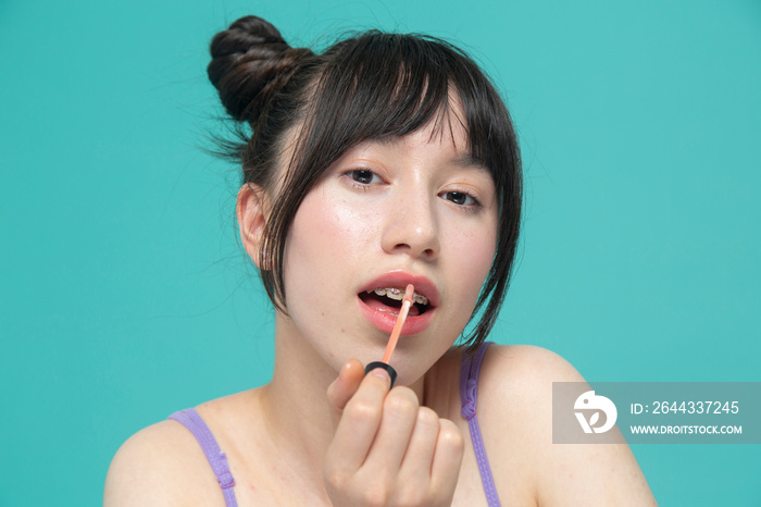 Studio portrait of girl applying lip gloss