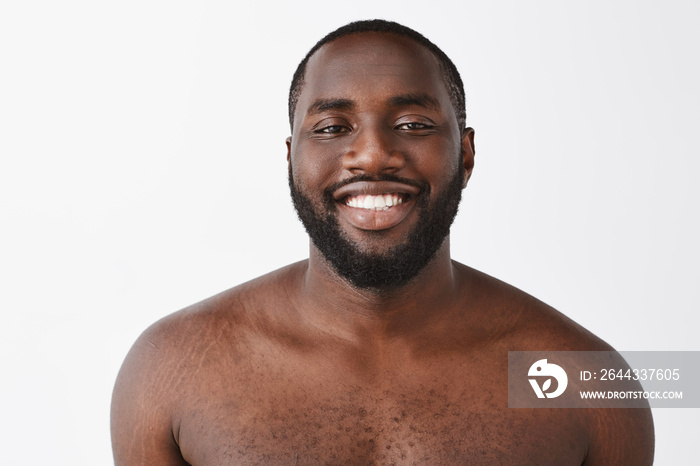 Beauty, people and emotions concept. Waist-up shot of happy handsome African American standing naked over gray background, smiling with satisfied and confident smile at camera