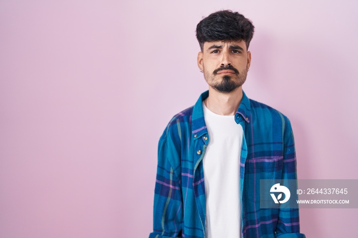 Young hispanic man with beard standing over pink background depressed and worry for distress, crying angry and afraid. sad expression.