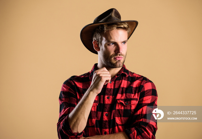 Handsome bearded macho. American cowboy. Beauty standard. Example of true masculinity. Cowboy wearing hat. Western life. Man unshaven cowboy beige background. Unshaven guy in cowboy hat