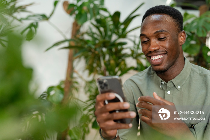 Young man with smartphone sitting in office lounge