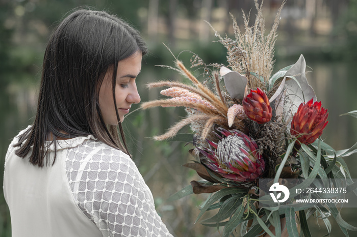 Portrait of an girl with a bouquet of exotic flowers.