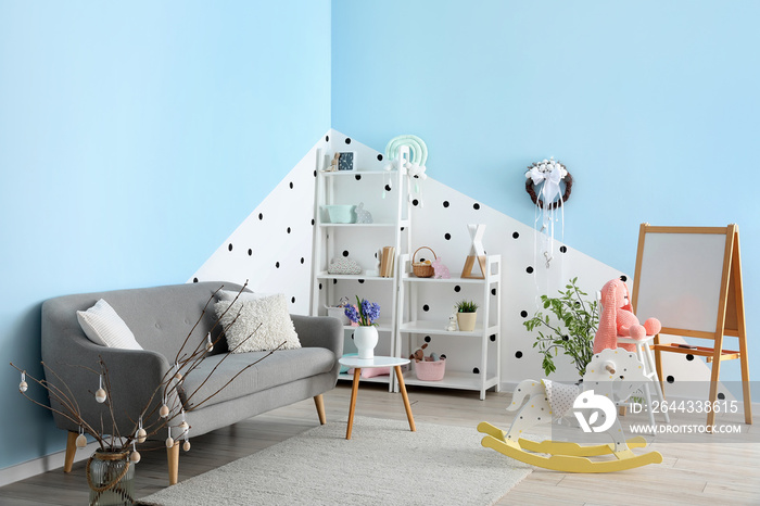 Interior of children’s room with Easter wreath, shelving units and sofa