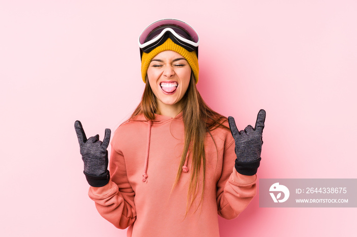 Young caucasian woman wearing a ski clothes isolated showing rock gesture with fingers
