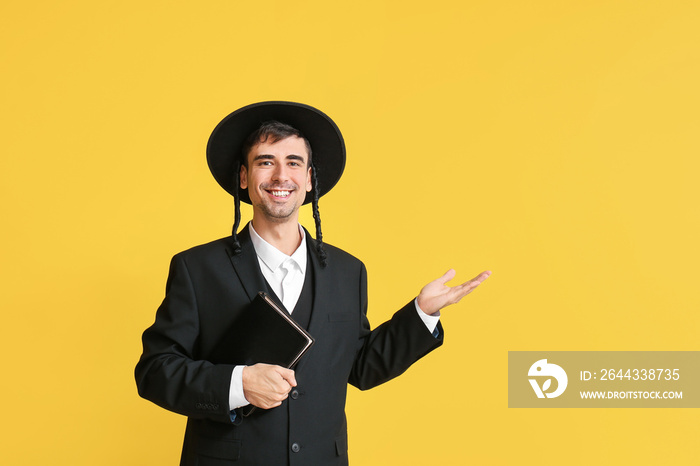 Hasidic Jewish man with Torah showing something on color background