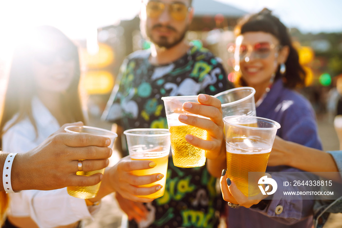 Young happy friends drinking beer and having fun at music festival together. Beach party, summer holiday, vacation concept. Friendship and celebration concept.