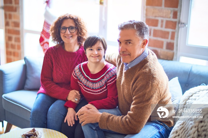 Beautiful family smiling happy and confident. Sitting on the sofa with smile on face hugging around christmas decorations at home