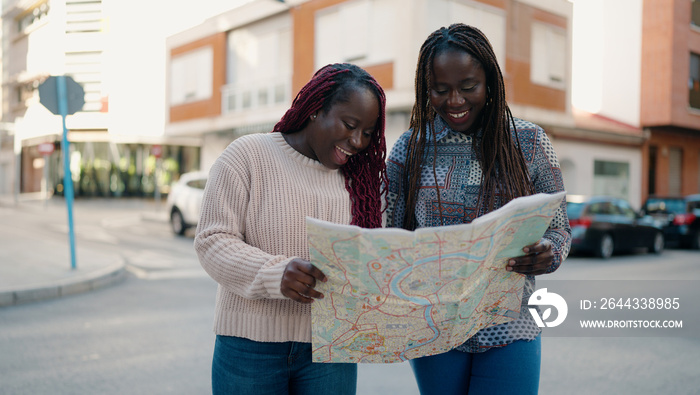 Two african american friends smiling confident looking city map at street