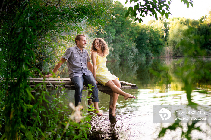 Lovely couple has fun sitting near lake.