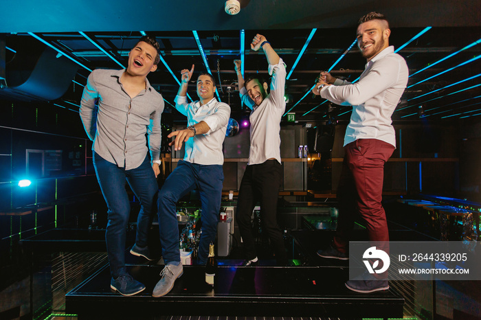 Group of smiling male friends having fun in night club