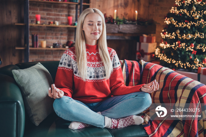 Portrait of attractive dreamy cheery girl sitting on divan wearing festal pullover meditating at modern loft industrial style indoors