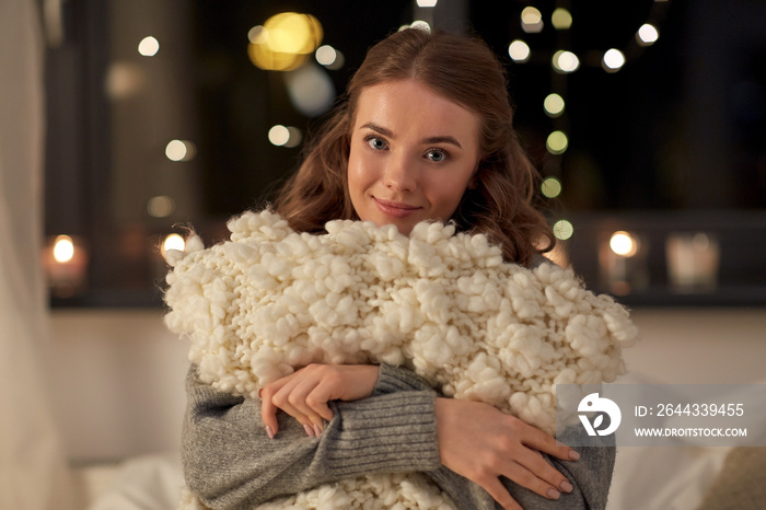 christmas, holiday and people concept - happy young woman with soft pillow in bed at home bedroom at night