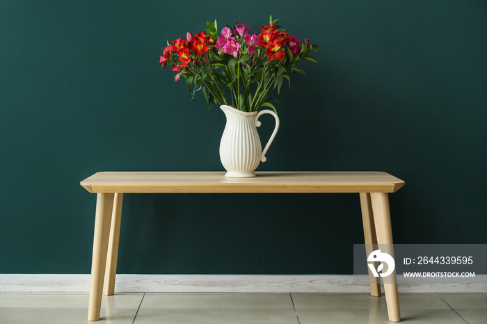 Vase with alstroemeria flowers on table near color wall