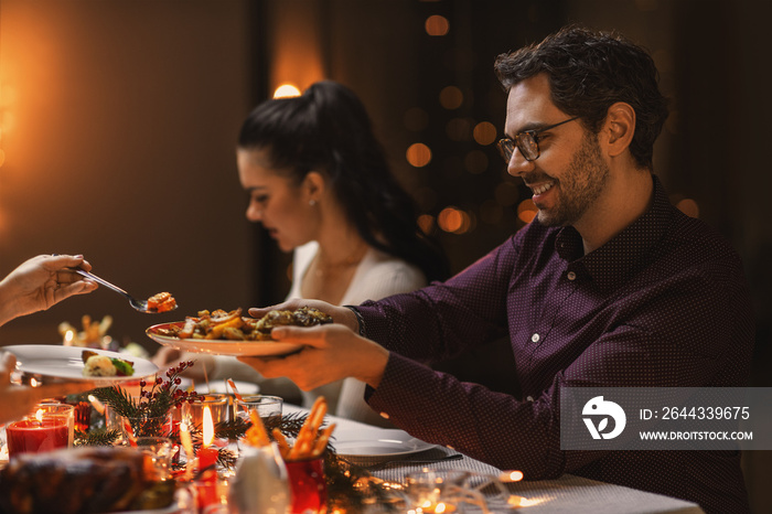 holidays, party and celebration concept - happy man with friends having christmas dinner at home