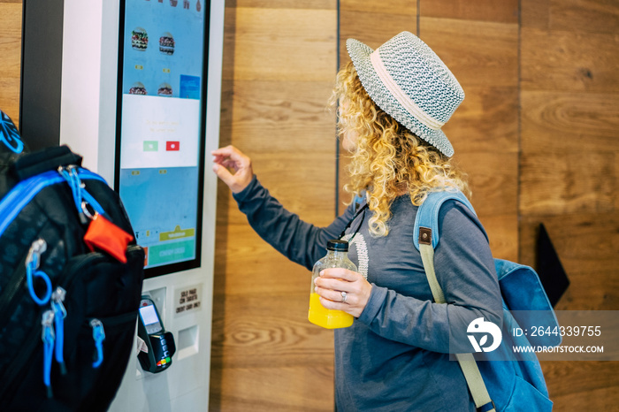 one adult woman choosing, her food in a restaurant or bar with a touch screen distributor in some fast food - curly lady choosing what to eat at luch or dinner