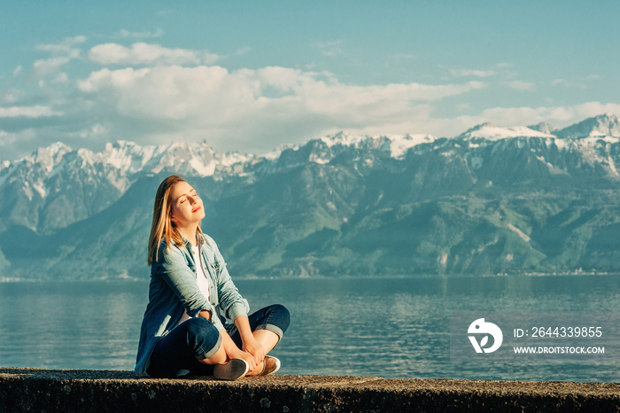 Outdoor portrait of happy young woman relaxing by the lake on a nice sunny day, peacful and harmonious mood