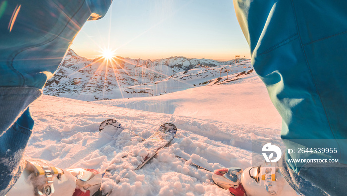 Skier athlete standing in front of wonderful sunset in ski resort - Winter extreme sport concept with person on top of the mountain ready to ride down - Focus on intersection skis