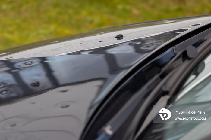 Car engine hood with many hail damage dents show the forces of nature and the importance of car insurance and a replacement value insurance against hail storm and storm hazards or extreme weather