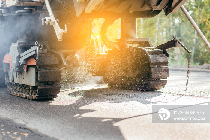 Road milling machine removes asphalt from old road and loads milled asphalt in dump truck.