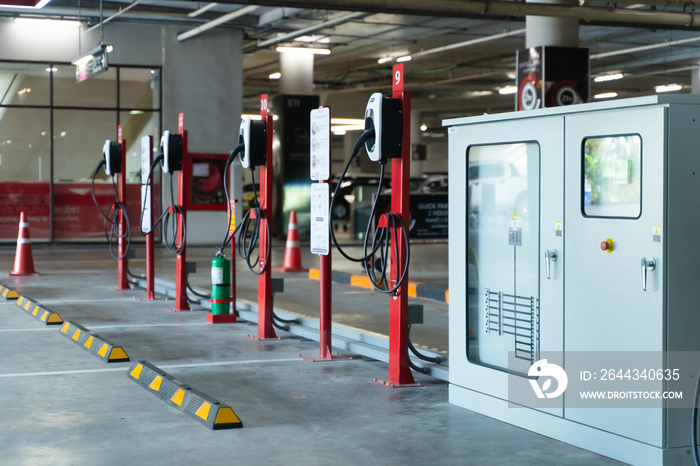 Electric car charging station for charge EV battery. Plug for vehicle with electric engine. EV charger. Clean energy. Charging point at car parking lot. Green power. Future transport technology.