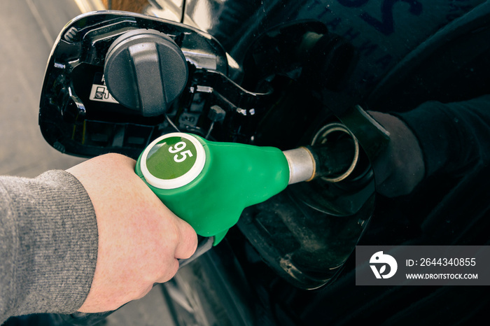 A man pumping gasoline fuel in car at gas station.