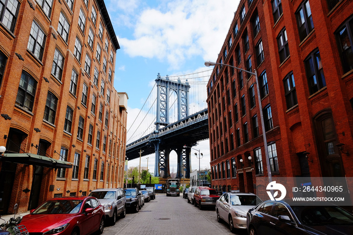 Manhattan bridge seen from a red brick buildings in Brooklyn street in perspective, New York, USA. Beautiful classic apartments in New York City. Beautiful american street. Famous view.