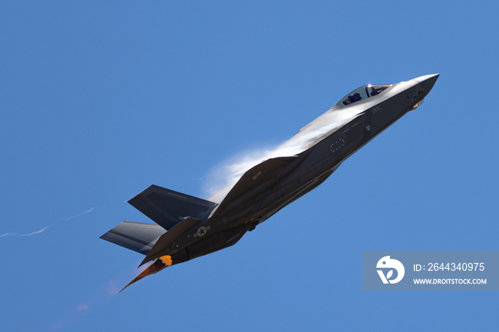 Very unusual close view of a F-35A Lightning II in a high G maneuver , with condensation clouds around the plane and afterburner on