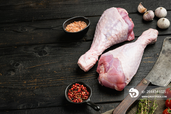 Raw turkey legs ingredients , with old butcher cleaver knife, on black wooden table background, with copy space for text