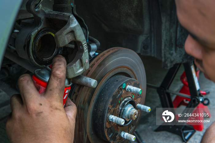 Close up mechanic repairing disk break with spraying oil