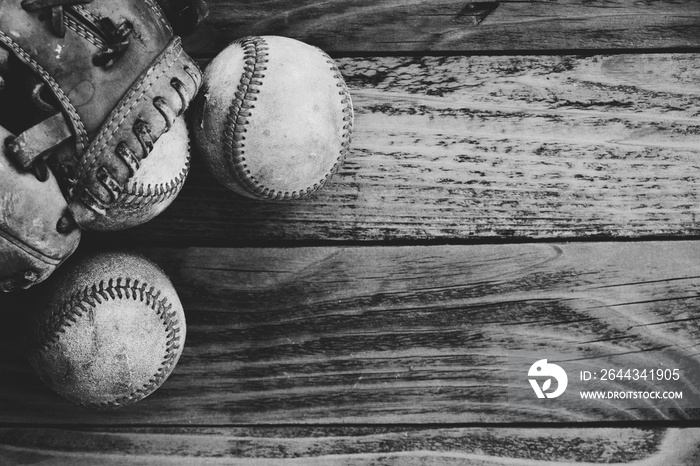 Grunge baseball background in black and white with group of balls and glove on wood texture.