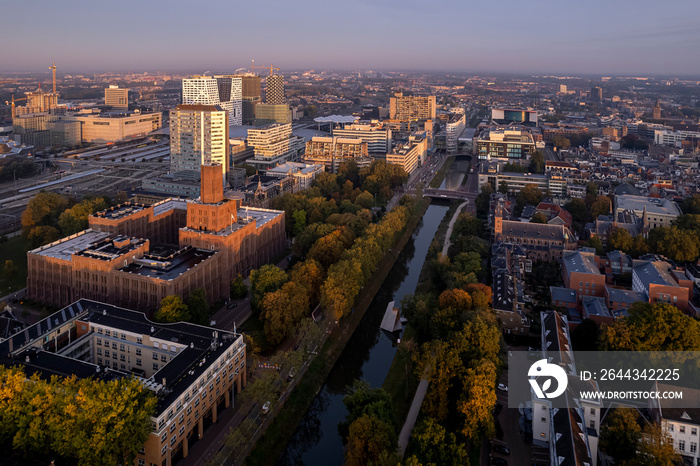 Inktpot building with UFO resting on its facade in central train station area along a canal with autumn colored trees at early morning sunrise. Aerial cityscape in The Netherlands