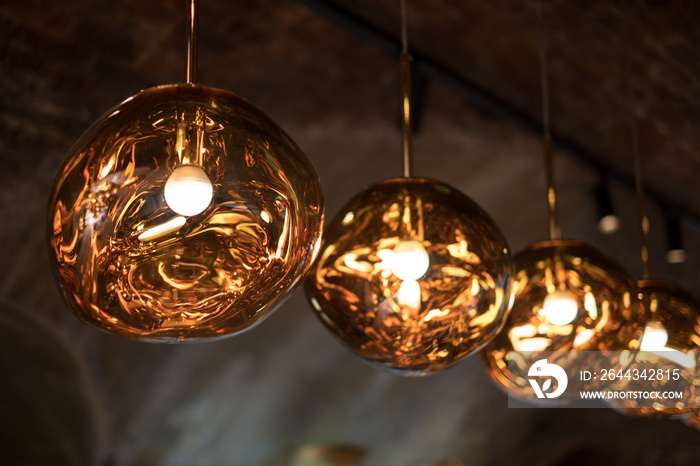 Row of Tom Dixon spherical metallic pendant lights hanging in the Tom Dixon flagship store and showroom at Coal Drops Yard, Kings Cross, London UK