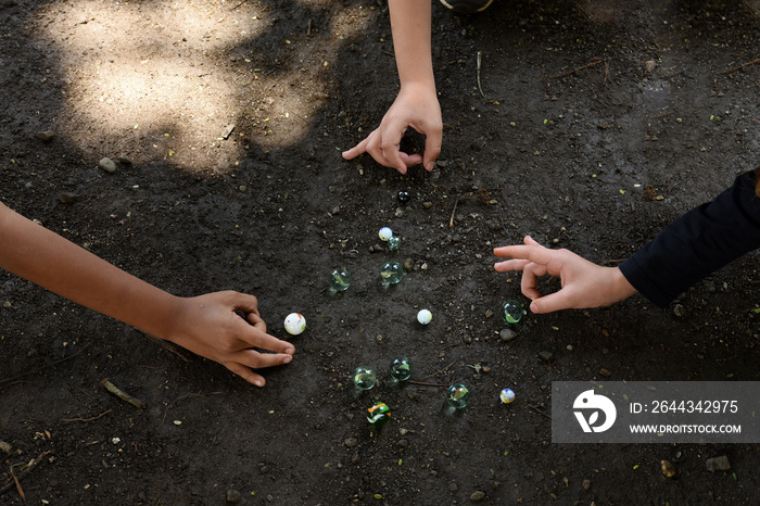 Children playing with marbles in the yard of the house. Traditional game, shared section of group game, inclusion  and Socialization