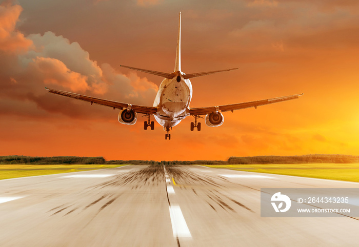 Passenger airplane landing at sunset on a runway.