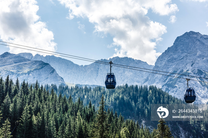 Two cabs of the cableway and skiers on the slope of the mountain Chopok south side on a sunny day in the ski