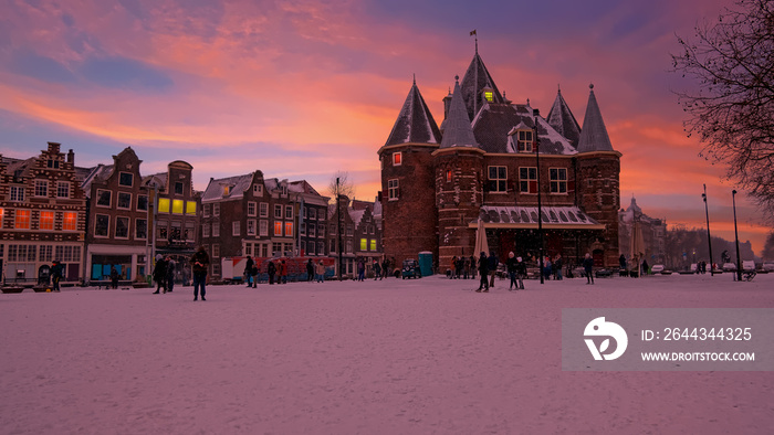 Snowy Nieuwmarkt with the Waag building in the city center from Amsterdam in the Netherlands in winter at sunset