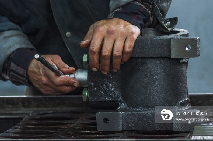 A close-up of a man’s hands smeared in oil twists a bolt into the pump housing