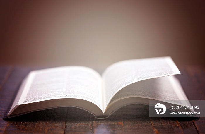 A Bible Open on a Rustic Wooden Table with Pages Blowing Open