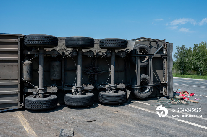 The truck is lying on its side in a car accident on the highway