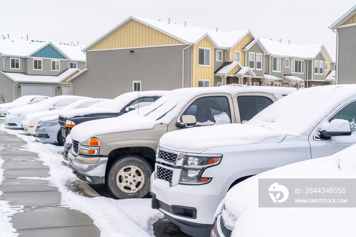 Cars in the parking lot of a neighborhood against homes and apartments in winter