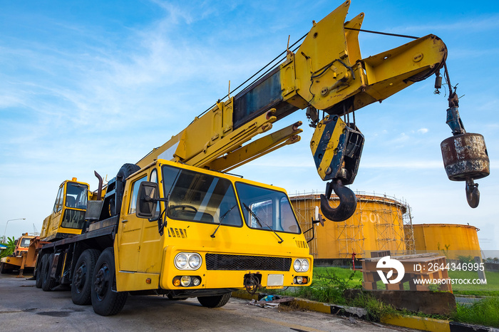 Yellow mobile crane against fuel oil storage tank area in power